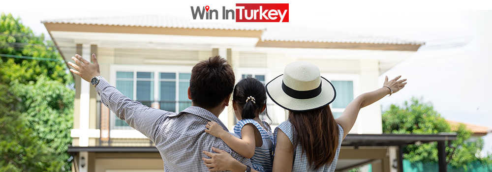 Ailesiyle yeni bir evin önünde mutlu bir şekilde duran bir çift ve çocuk.